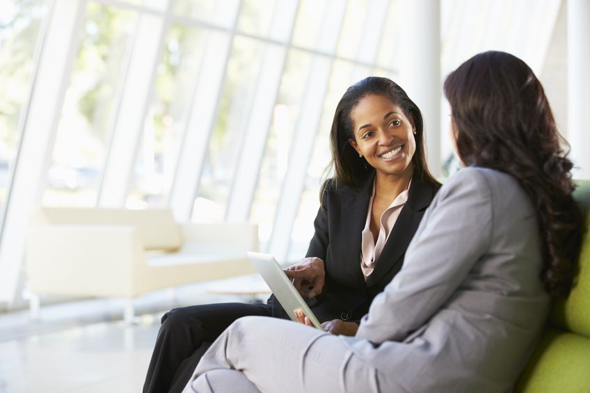 4 Phrases You Should Use in Mentoring 7 A mentor and mentee with digital tablet sitting in a modern office.