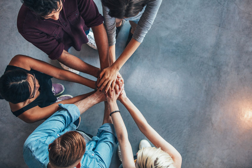4 Phrases You Should Use in Mentoring 6 Top view of mentors and mentees putting their hands on top of each other in support.
