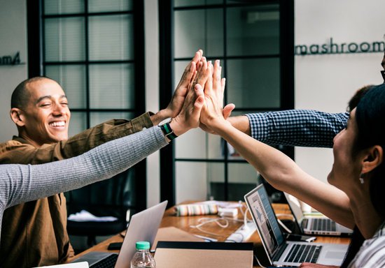 Challenges with Managing a Traditional Mentoring Program 7 Team of coworkers high five together with each other to celebrate.