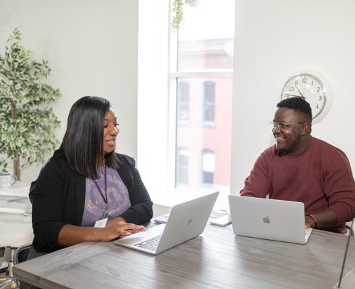 5 Ways to Personalize the Mentoring Experience 5 Two employees sitting in an office at computers discussing their mutual mentoring experience.
