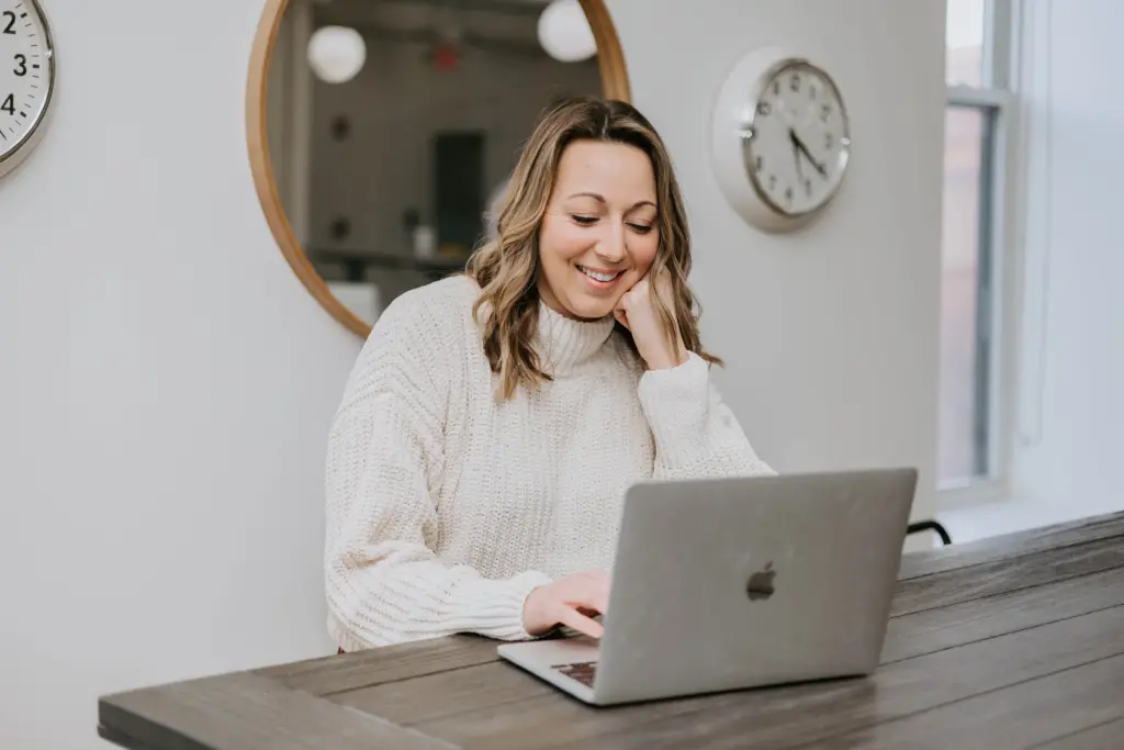 What Is Employee Management? A Starting Guide for Giving (Almost) Everyone What They Want 5 Female employee sitting at a table engaged in productive work at a laptop.