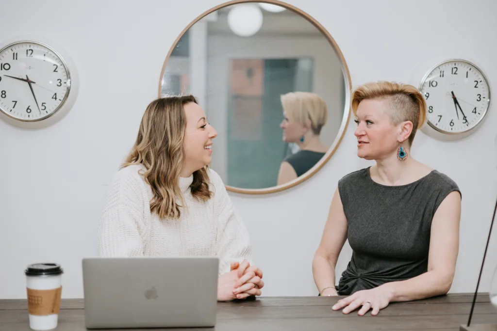 Mentor Meetings: Best Practices and Tips for Successful Conversations 5 Two women at a table in an office discussing future mentor meetings.