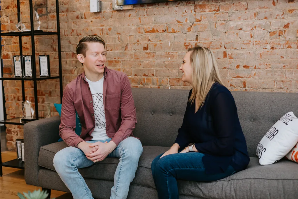 Mentor Meetings: Best Practices and Tips for Successful Conversations 4 Man and women on a couch engaging in a mentor meeting conversation.