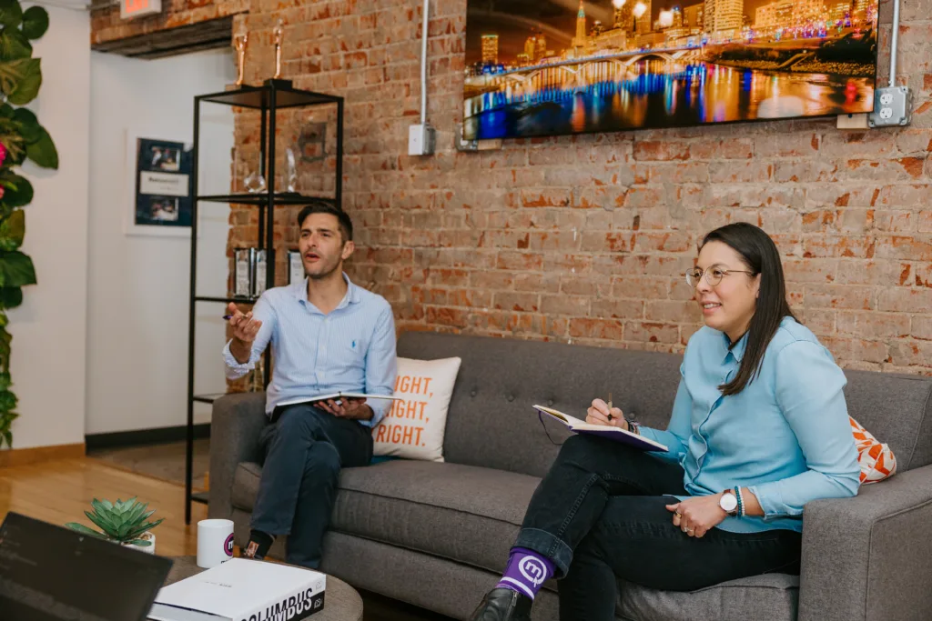 Bias for Action: Psychological Hack to Increase Productivity at Work 6 Team members in an office on a couch using bias for action to boost productivity.
