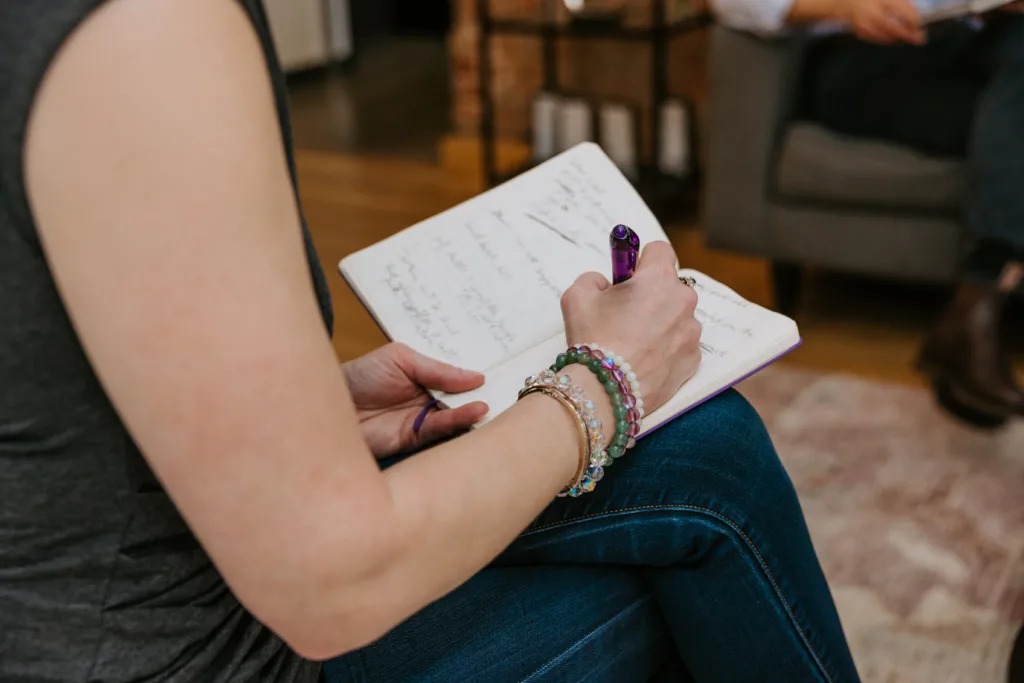 How to Talk About Career Aspirations In Interviews 8 Woman writing in a journal about her career aspirations.