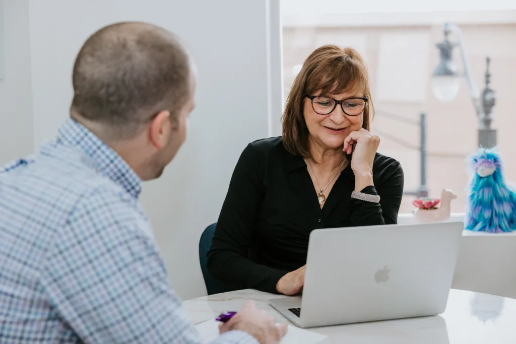 5 Employee Development Strategies that Will Increase Retention 8 Man and woman engaged in employee development plan meeting at a small table in an office.