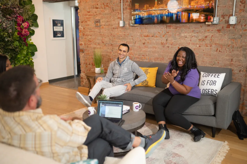 Reverse Mentoring: 11 Tips for Making It Work 7 Group of employees engaging in discussion on a couch during reverse mentoring engagement.