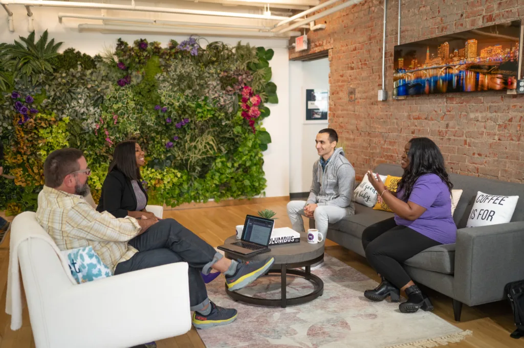 5 Employee Development Strategies that Will Increase Retention 7 Employee development in an office with 4 employees sitting on coaches and chairs.