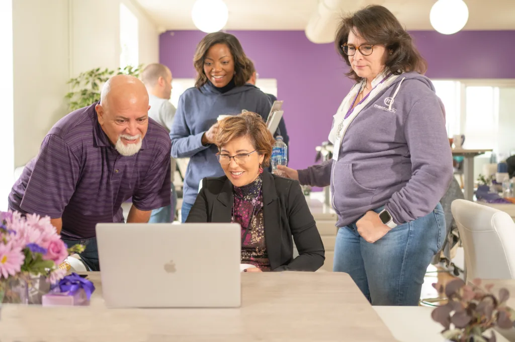 Inclusive Culture: How to Create an Inclusive Workplace Culture 5 Image of diverse team members in an inclusive work space looking at a computer together.