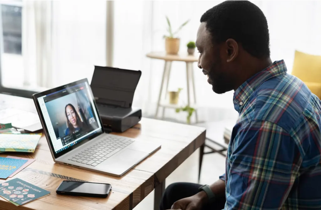 How to Be An Effective Mentor (and Help Other Mentors Succeed) 4 A man practicing how to be an effective mentor by having a conversation with a mentee on a video call.