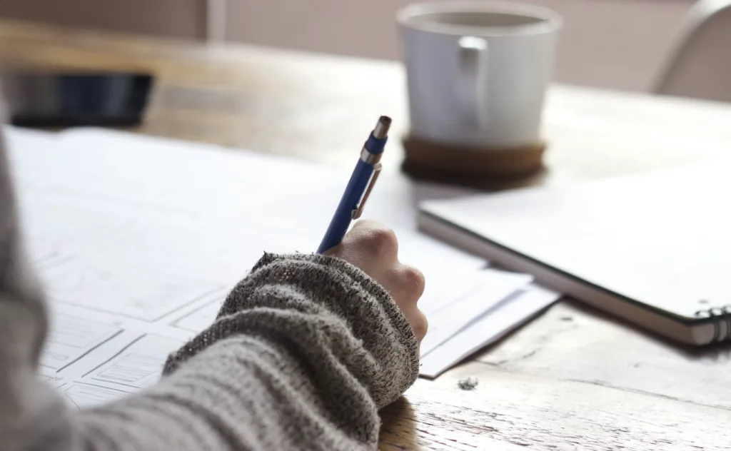 Peer Mentor Programs: How They Work and How to Start Them 8 Woman writing on a paper for mentoring goals.
