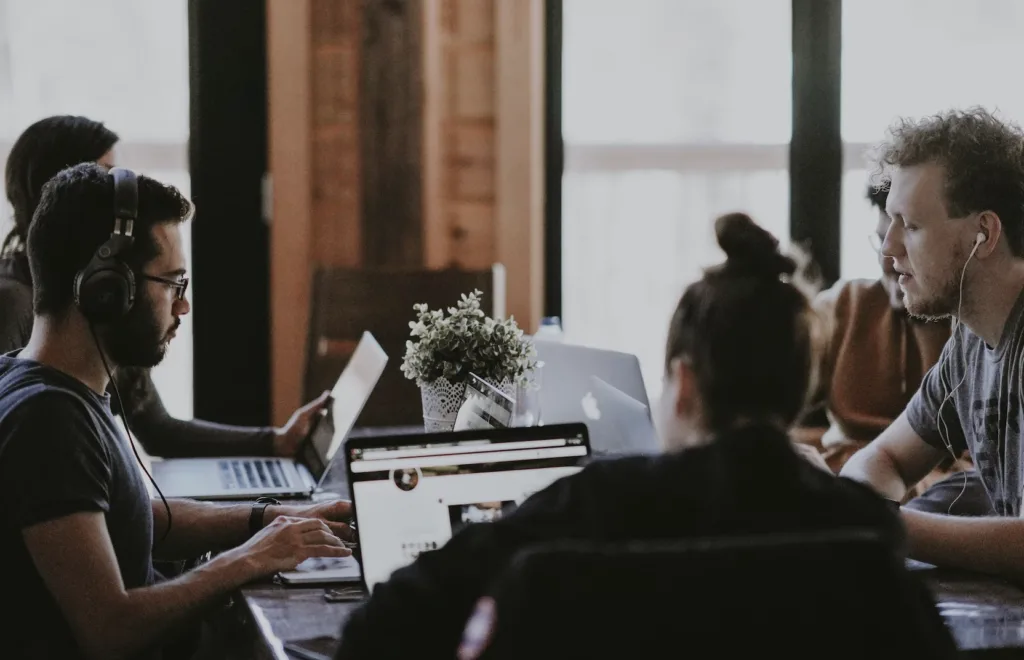 8 Examples of Team Culture Types to Emulate 6 Workers sitting at a desk enjoying positive team culture.