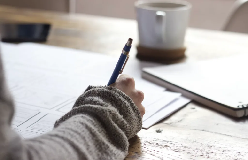 Sales Mentorship: Benefits and Tips for a Successful Sales Mentorship Program 5 Woman writing down goals on a paper for her sales mentorship program.