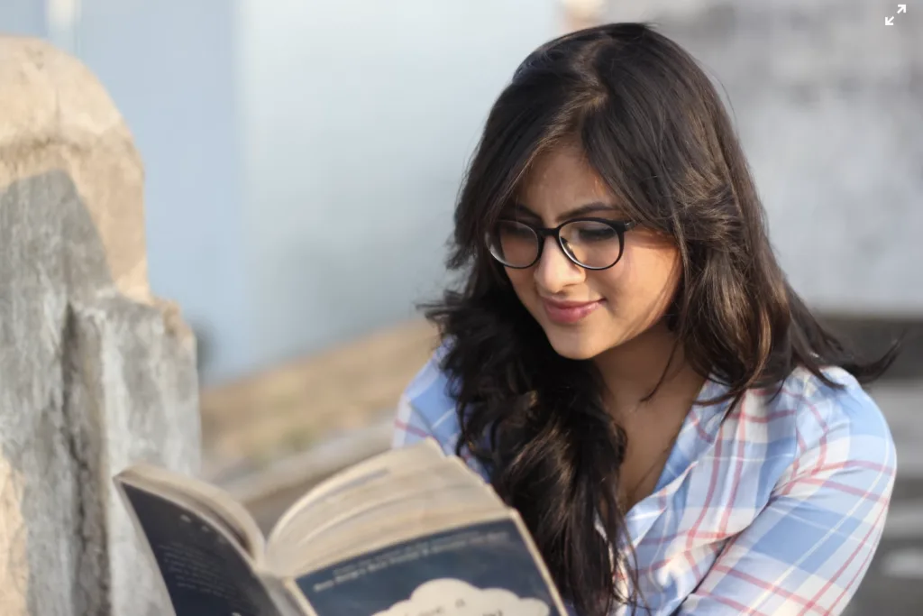 Mentoring Activities: Our 10 Favorite Mentoring Activities to Boost Engagement 9 A woman holding and reading a book outside.