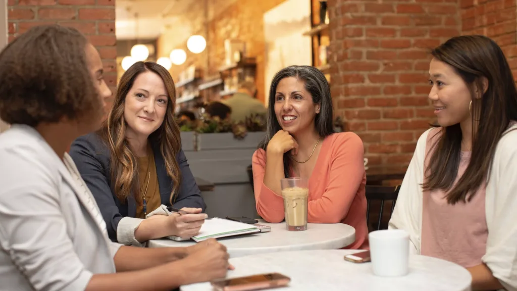 Mentoring Activities: Our 10 Favorite Mentoring Activities to Boost Engagement 7 Four women in a mentoring relationship engaged in a mentoring activity of drinking coffee.